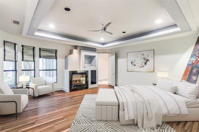 bedroom featuring hardwood / wood-style flooring, ceiling fan, and a tray ceiling