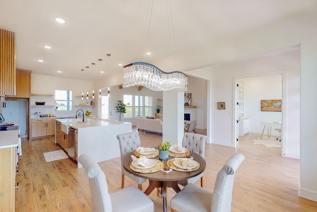 dining area with light wood-type flooring, sink, and a notable chandelier