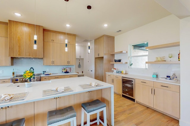 kitchen with stainless steel range with electric stovetop, beverage cooler, a breakfast bar, light brown cabinetry, and light hardwood / wood-style floors