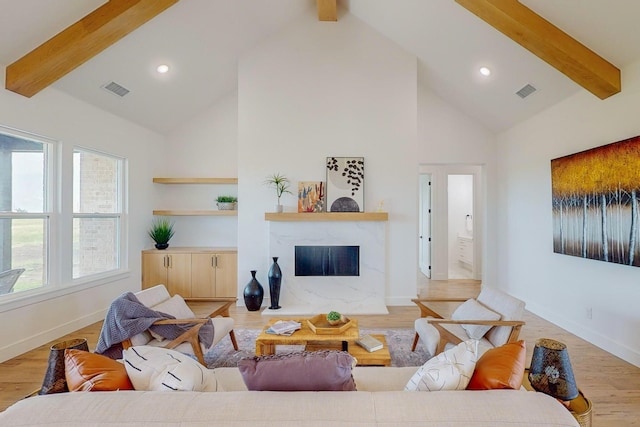 living room with a high end fireplace, light hardwood / wood-style floors, beamed ceiling, and high vaulted ceiling