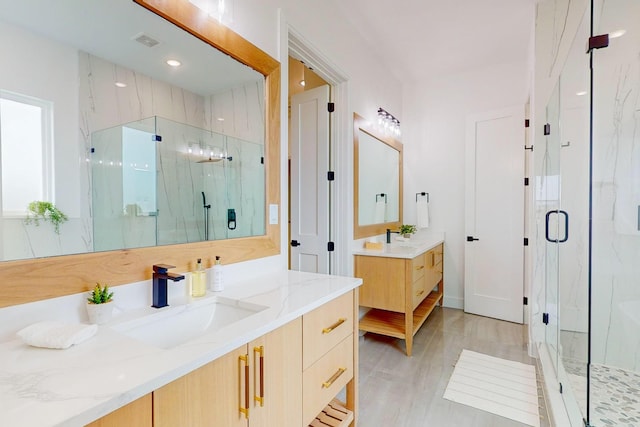 bathroom with wood-type flooring, vanity, and a shower with door