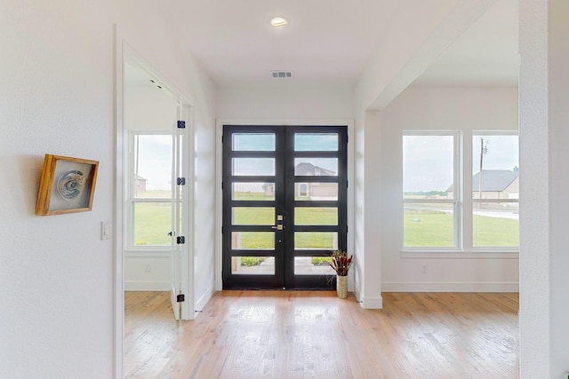 entrance foyer with french doors and light hardwood / wood-style floors