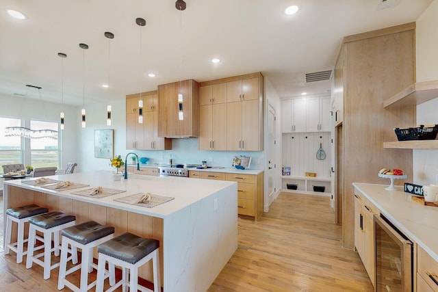 kitchen with light brown cabinets, beverage cooler, and light wood-type flooring