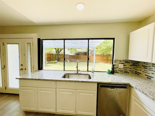 kitchen with light hardwood / wood-style flooring, sink, light stone countertops, decorative backsplash, and stainless steel dishwasher