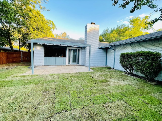 rear view of house with a lawn and a patio