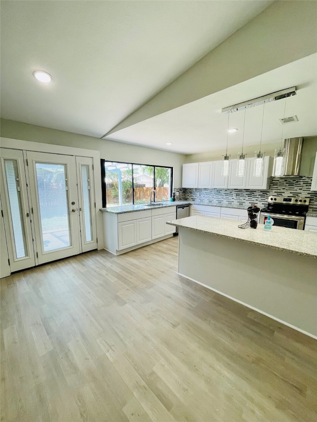 kitchen with light hardwood / wood-style flooring, appliances with stainless steel finishes, hanging light fixtures, decorative backsplash, and white cabinetry