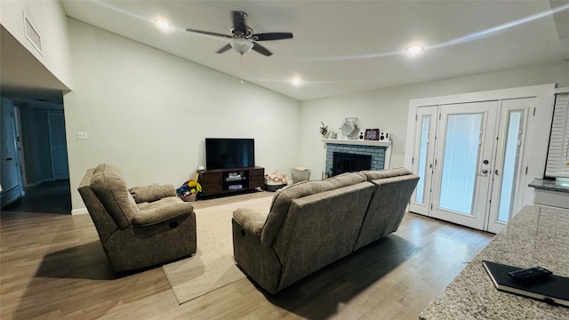 living room featuring lofted ceiling, ceiling fan, hardwood / wood-style floors, and a brick fireplace