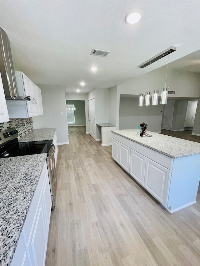 kitchen featuring pendant lighting, light stone counters, light wood-type flooring, and white cabinetry