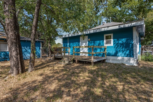 back of property featuring a lawn and a wooden deck