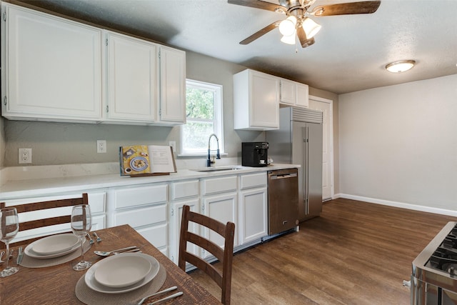 kitchen with a textured ceiling, white cabinets, appliances with stainless steel finishes, dark wood-type flooring, and sink