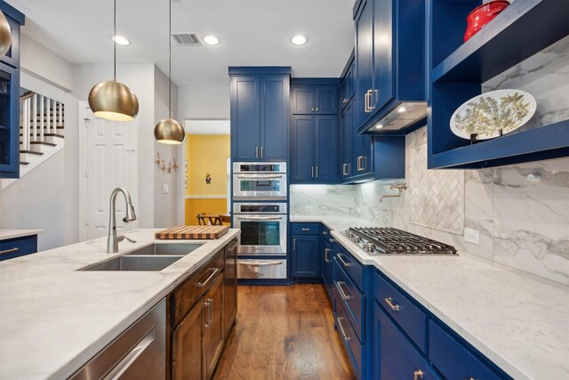 kitchen featuring a center island with sink, stainless steel appliances, a breakfast bar, blue cabinets, and tasteful backsplash