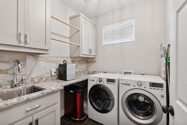 washroom with cabinets, dark tile patterned flooring, washer and clothes dryer, and sink