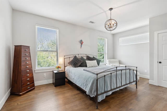 bedroom featuring a notable chandelier, multiple windows, and wood-type flooring