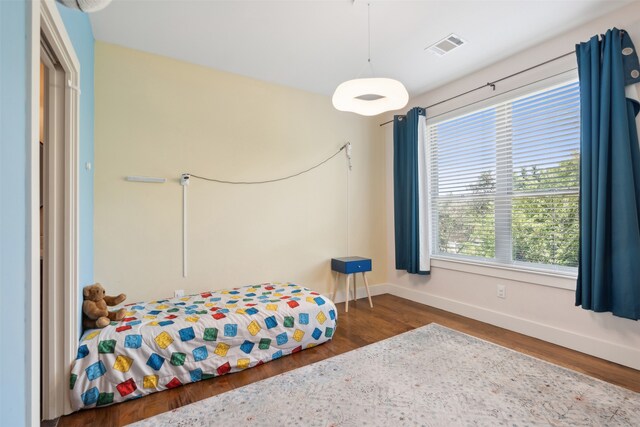 bedroom featuring multiple windows and dark hardwood / wood-style floors