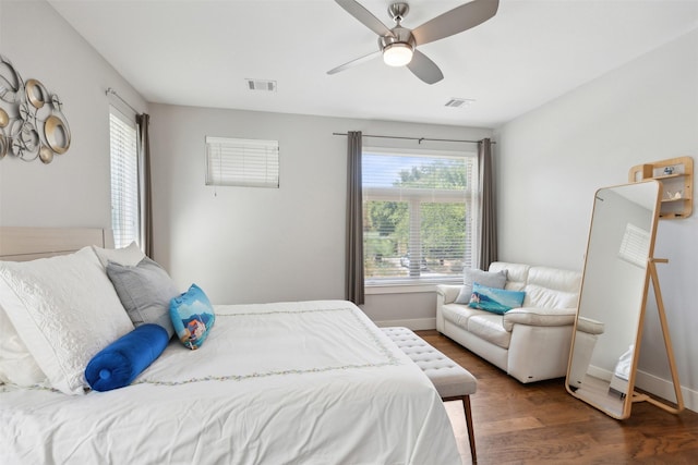 bedroom featuring a ceiling fan, visible vents, baseboards, and wood finished floors