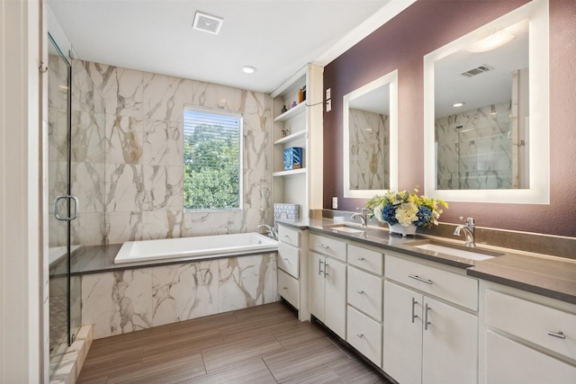 bathroom featuring a garden tub, a marble finish shower, double vanity, visible vents, and a sink