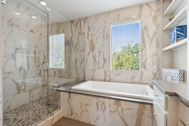 bathroom with a garden tub, a wealth of natural light, a marble finish shower, and vanity