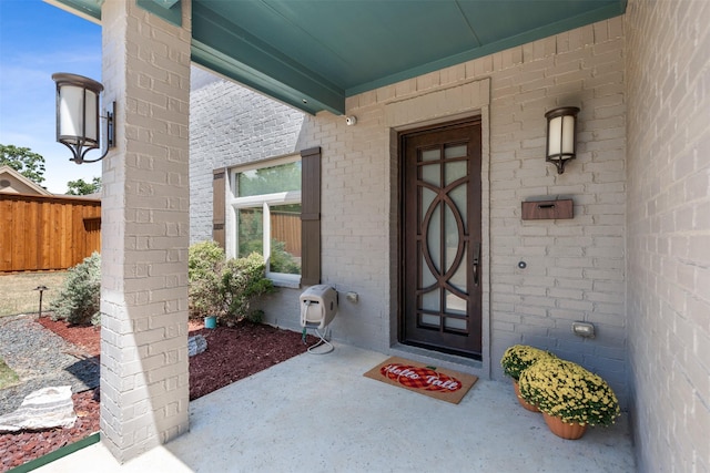 property entrance featuring brick siding and fence