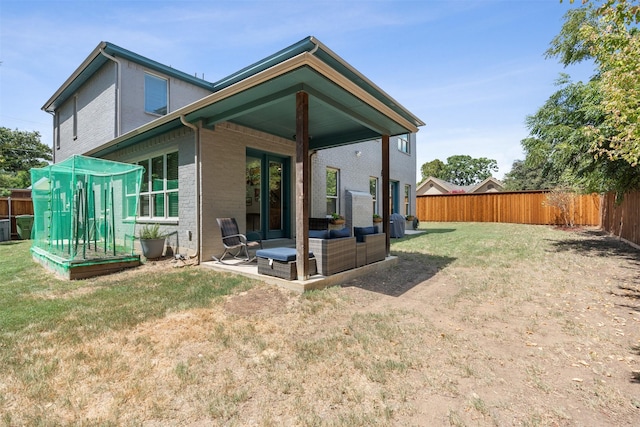 back of house with a fenced backyard, a lawn, and brick siding