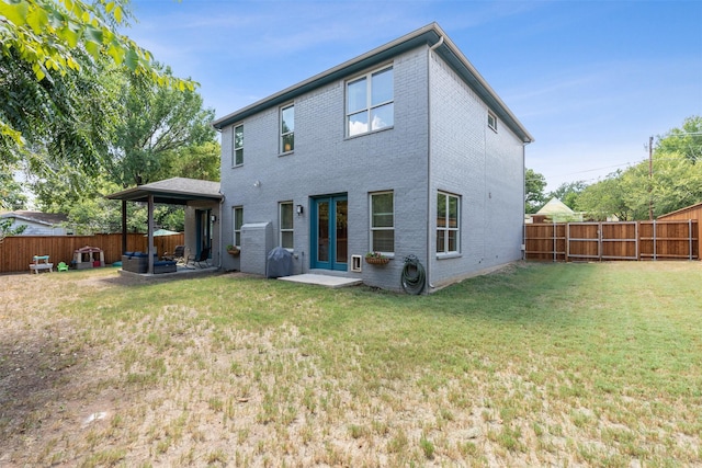 rear view of house featuring a fenced backyard, a lawn, and brick siding