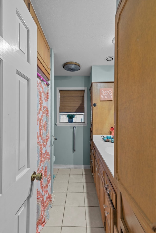 bathroom featuring tile patterned floors, toilet, a textured ceiling, and vanity