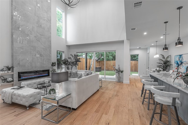 living room with light hardwood / wood-style floors, a high ceiling, and a fireplace