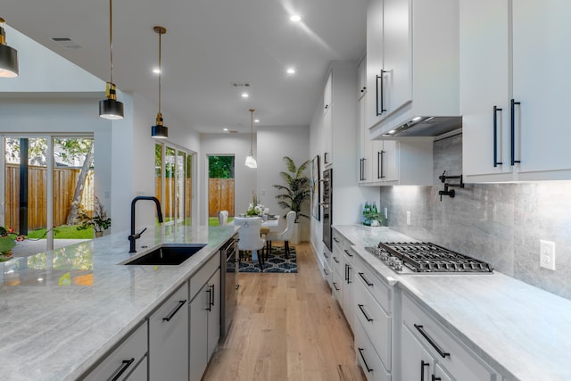 kitchen featuring appliances with stainless steel finishes, white cabinetry, sink, and light stone counters