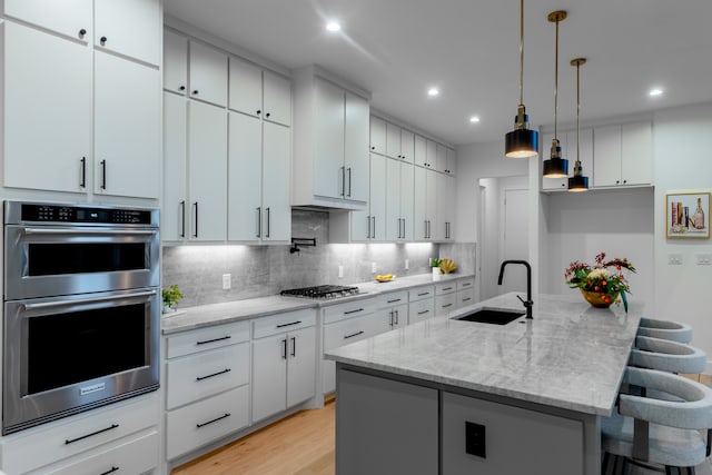 kitchen featuring an island with sink, white cabinets, sink, and stainless steel appliances