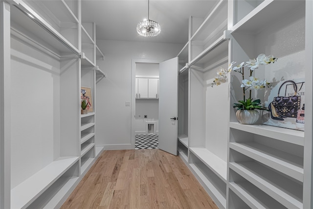 spacious closet featuring light hardwood / wood-style floors and a chandelier