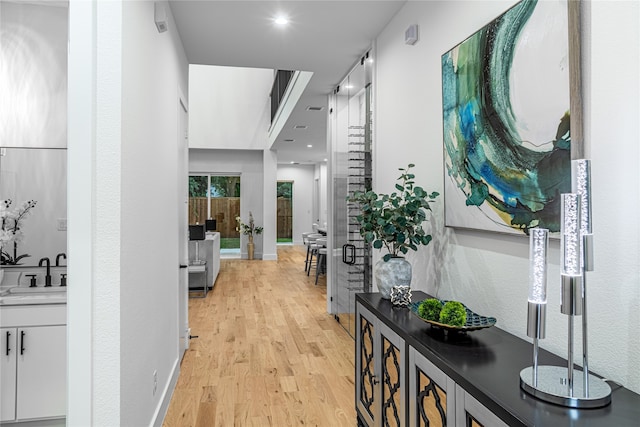 corridor with light hardwood / wood-style flooring and sink