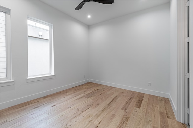 empty room with ceiling fan, a wealth of natural light, and light wood-type flooring