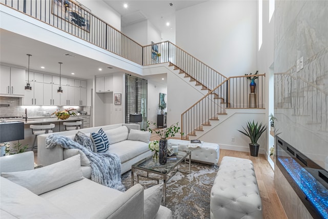 living room featuring light wood-type flooring and a towering ceiling