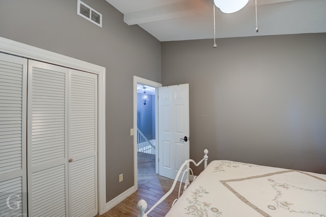 bedroom with a closet, hardwood / wood-style flooring, and lofted ceiling with beams