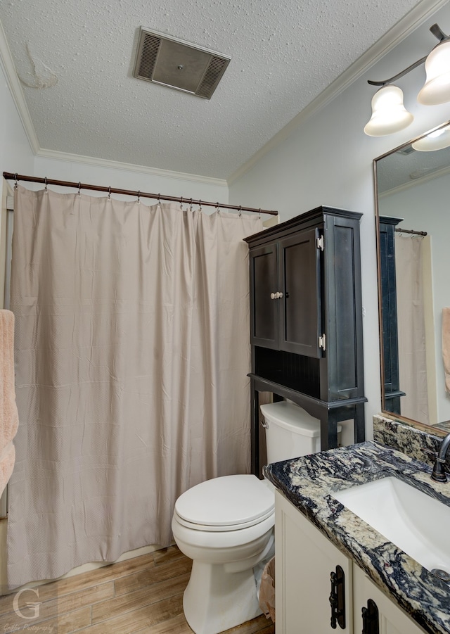 bathroom featuring toilet, hardwood / wood-style floors, ornamental molding, vanity, and a textured ceiling