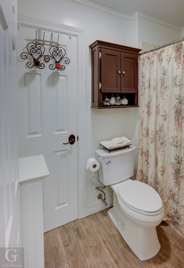 bathroom featuring wood-type flooring, toilet, crown molding, and a textured ceiling