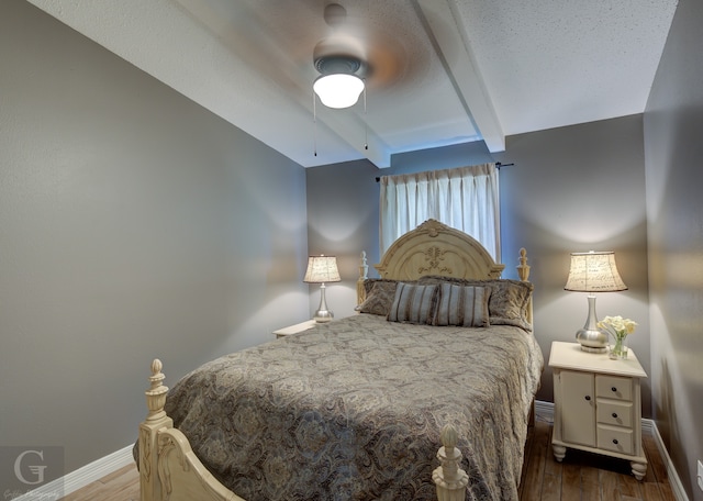 bedroom featuring lofted ceiling with beams, hardwood / wood-style floors, and ceiling fan