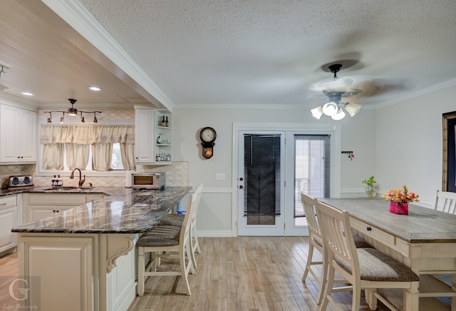 kitchen with ceiling fan, a wealth of natural light, light hardwood / wood-style floors, and tasteful backsplash