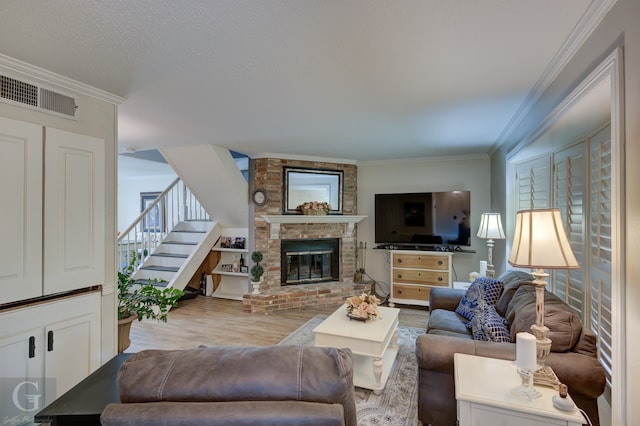 living room featuring crown molding, brick wall, wood-type flooring, and a brick fireplace