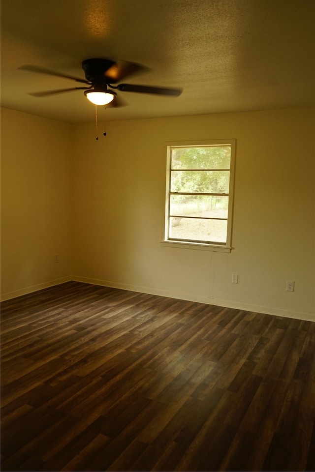 empty room with a textured ceiling, ceiling fan, and dark hardwood / wood-style flooring