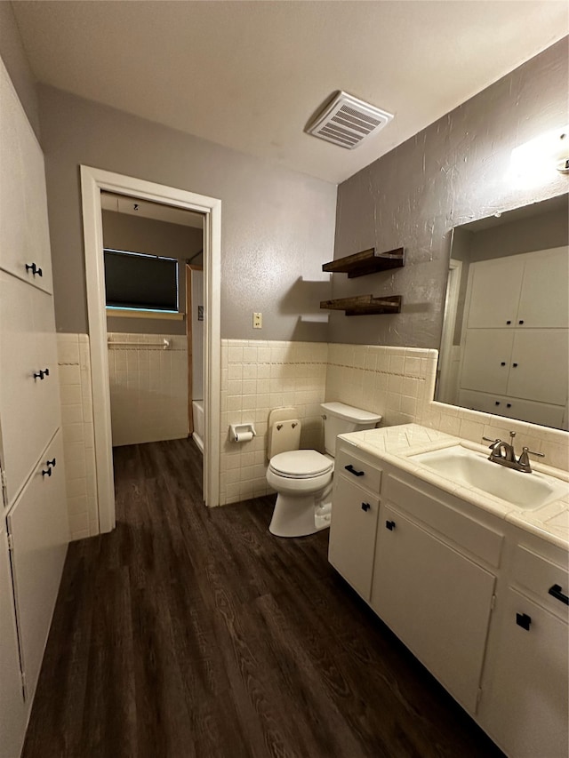 bathroom featuring tile walls, vanity, hardwood / wood-style floors, and toilet