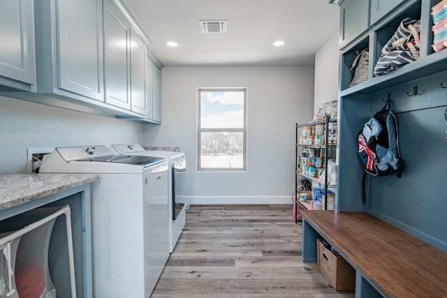 washroom with separate washer and dryer, light hardwood / wood-style flooring, and cabinets