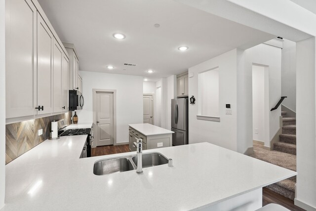 kitchen with sink, backsplash, dark wood-type flooring, stainless steel appliances, and a center island