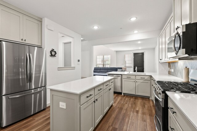 kitchen with a breakfast bar area, dark hardwood / wood-style flooring, stainless steel appliances, kitchen peninsula, and white cabinetry