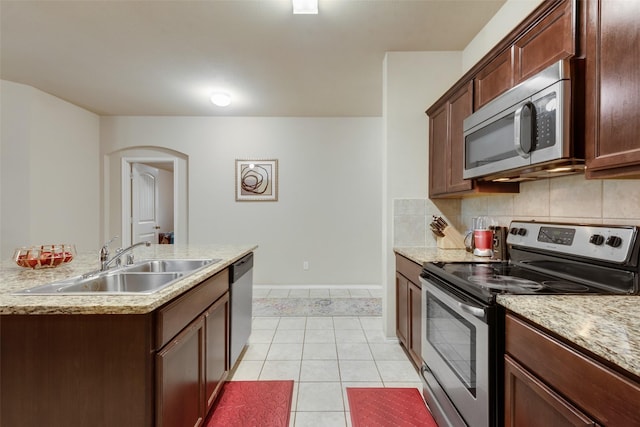 2512 Saldana Dr, Fate, TX 75189 - kitchen featuring stainless steel appliances, light tile patterned floors, arched walkways, and backsplash