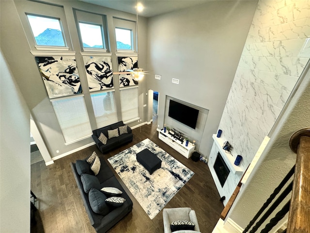 living room with ceiling fan, dark hardwood / wood-style floors, and a towering ceiling