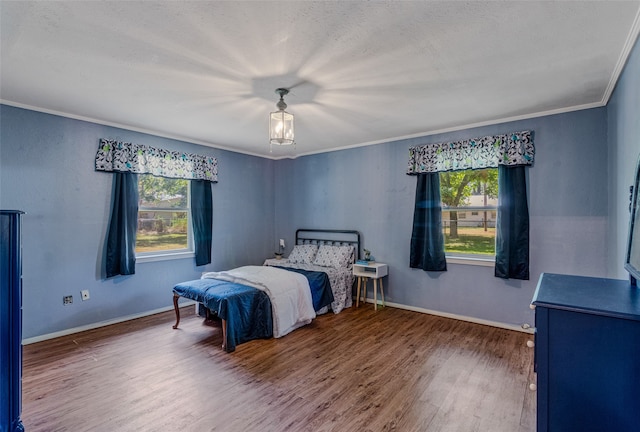 bedroom with wood-type flooring, crown molding, and a textured ceiling