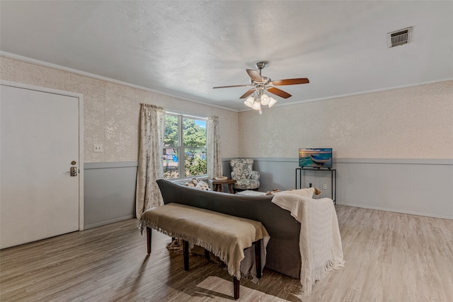 bedroom featuring light wood-type flooring, crown molding, ceiling fan, and a textured ceiling