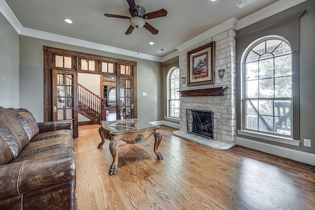 living room with a healthy amount of sunlight, ceiling fan, a stone fireplace, and wood-type flooring