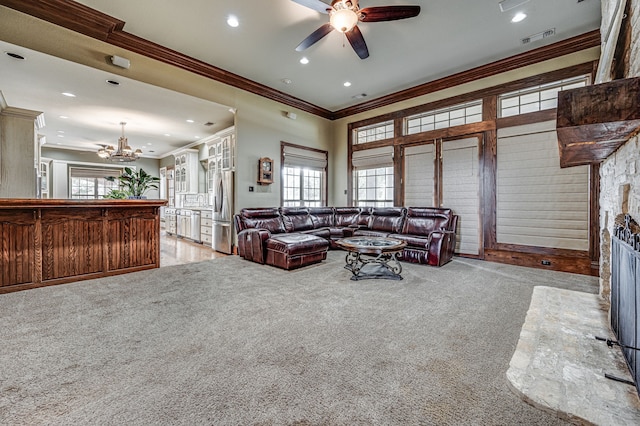 carpeted living room with crown molding, ceiling fan with notable chandelier, and a fireplace