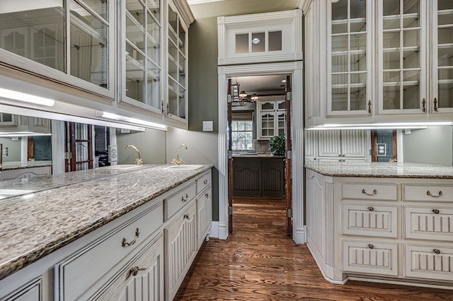 kitchen with light stone counters, dark hardwood / wood-style floors, sink, and white cabinetry